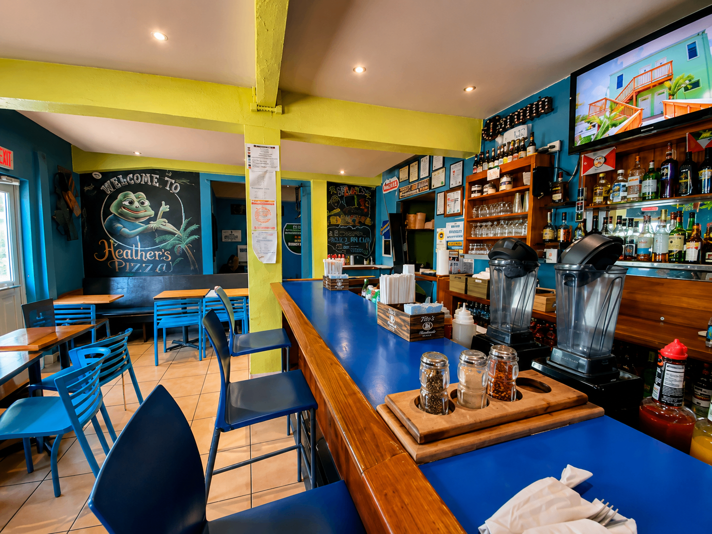 Heather's Pizza interior in downtown Culebra with blue bar, yellow beams, and welcome chalkboard mural