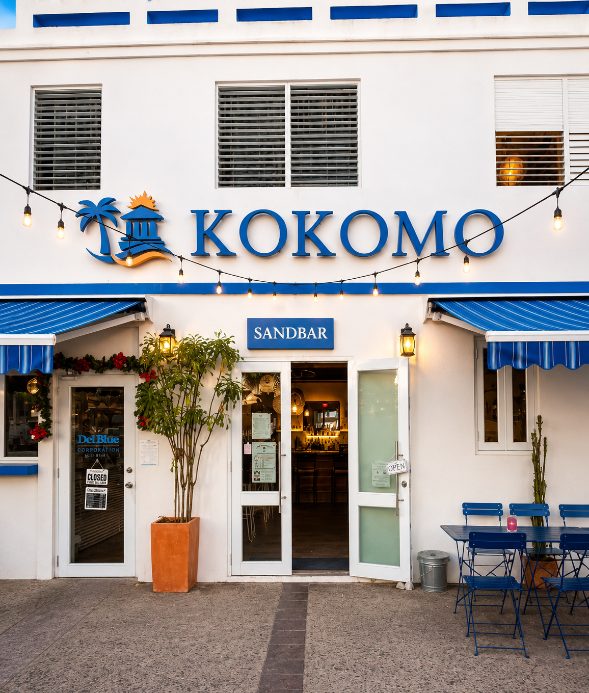 Sandbar — Kokomo building entrance with blue awnings and the Sandbar sign glowing at dusk