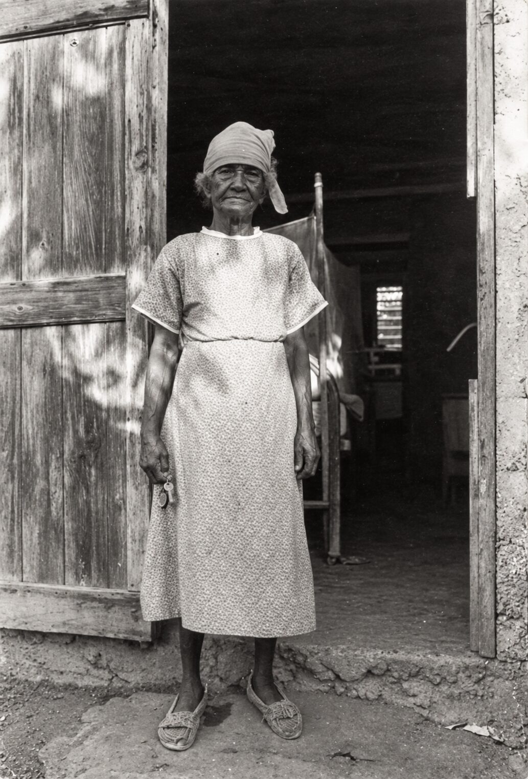 Doña Sandalia standing in the doorway of a wooden house in Culebra