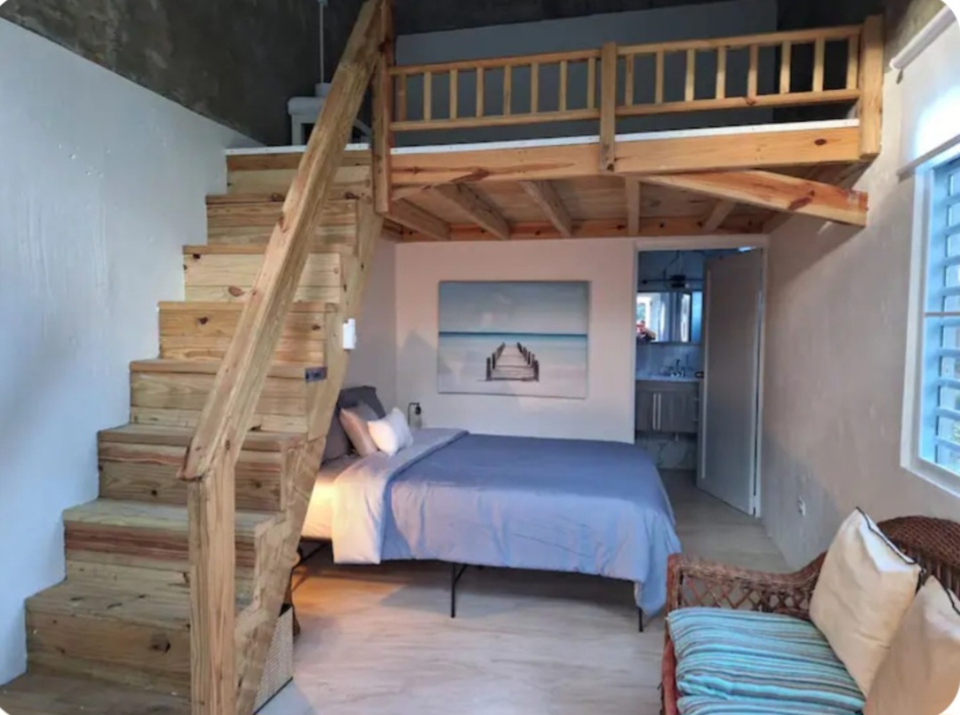 Interior of Seahorse Apartment — loft with wooden staircase and queen bed on the main level