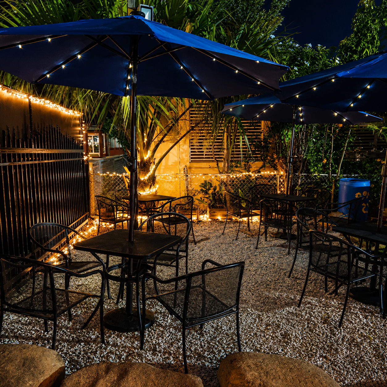 Rolls of Heaven — cozy outdoor evening seating with string lights and blue umbrellas